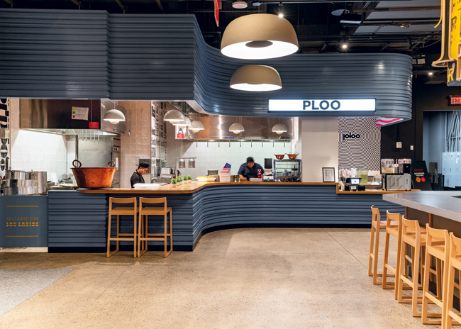 Food halls with a mix of dine-in and takeout restaurants, bars and retail offerings are a hot trend in office-building amenities. Olly Olly Market, which opened in the fall of 2022  on the ground floor of the Starrett-Lehigh Building in the Hudson Yards development in Manhattan, was developed by and is now managed by 16″ on Center, a company that has also created two ground-level food halls in downtown Chicago office buildings. In all three halls, tenants are limited to local operators.  Photos courtesy of 16OC