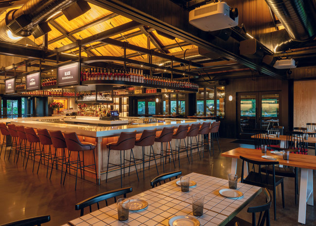 Set under a  double-height vaulted ceiling, 30 seats surround The Kitchen Table’s full-service bar.