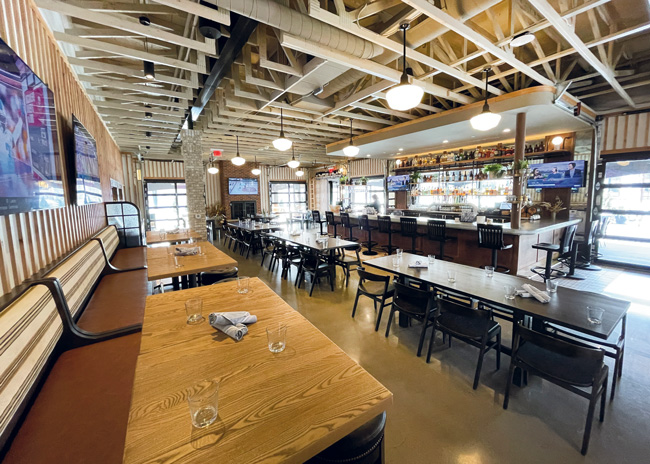 Exposed ceiling trusses and open liquor storage displays add to the modern, comfortable atmosphere.