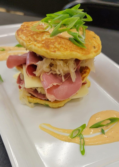 For its Street Eats monthly promotion, Metz Culinary Management often pairs  recognizable dishes with those that may be new to its diners, such as this Japanese okonomiyaki that’s topped with all the  ingredients of a Reuben sandwich.  Photo courtesy of Metz Culinary Management