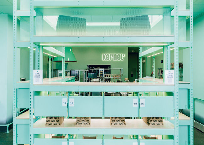 Designed to introduce a smaller, hyperefficient operating model,  Kernel’s kitchen features a robotic arm that loads food into a conveyorized induction oven for finishing to order.  Photos courtesy of Benedict Evans