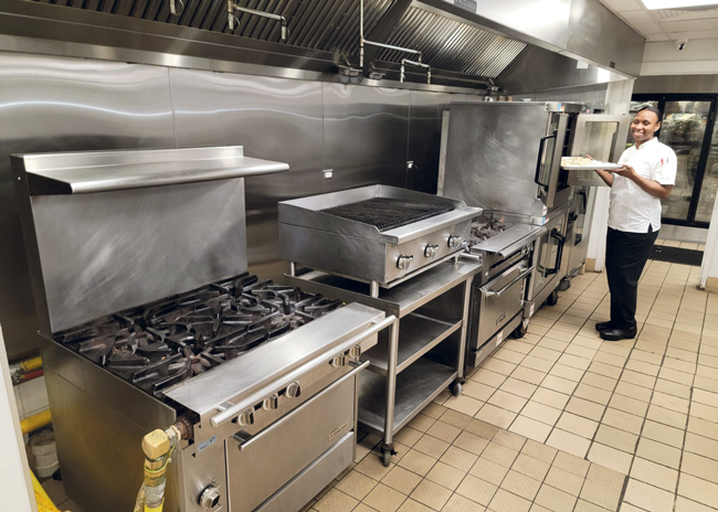 Pastry chef Geshann Pratt places a dessert in the convection oven in the main kitchen. 