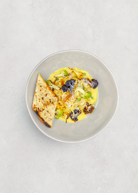 At Guckenheimer’s B&I accounts, a colorful Chickpea Spaghetti Carbonara dish includes mushroom pancetta, rainbow cauliflower, vegan parmesan and herb oil; it’s served with a grilled baguette.  Photo courtesy of Guckenheimer