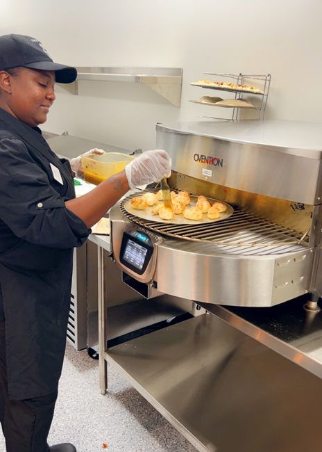 Sabrina Brewster prepares garlic knots on the circular oven.