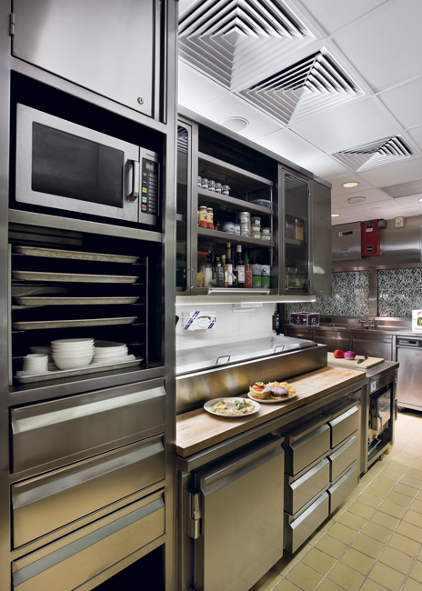 The service station at Dallas’ Fearings Restaurant in the Ritz-Carlton Hotel includes a microwave for quick heating and a wood top counter for prep, along with shelving and cold storage to store ingredients and dishware.  Photo courtesy of Ricca Design