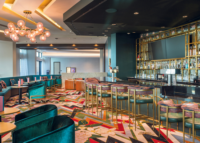 Proper & Plume Cocktail Lounge has a hidden entrance and offers craft cocktails and live music. The lounge bar displays a playful flamingo-themed design, vibrant colors and eclectic decor.