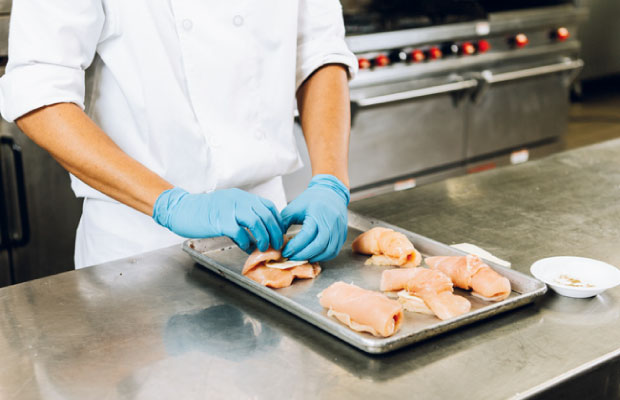 Chef preparing chicken dish with gloves